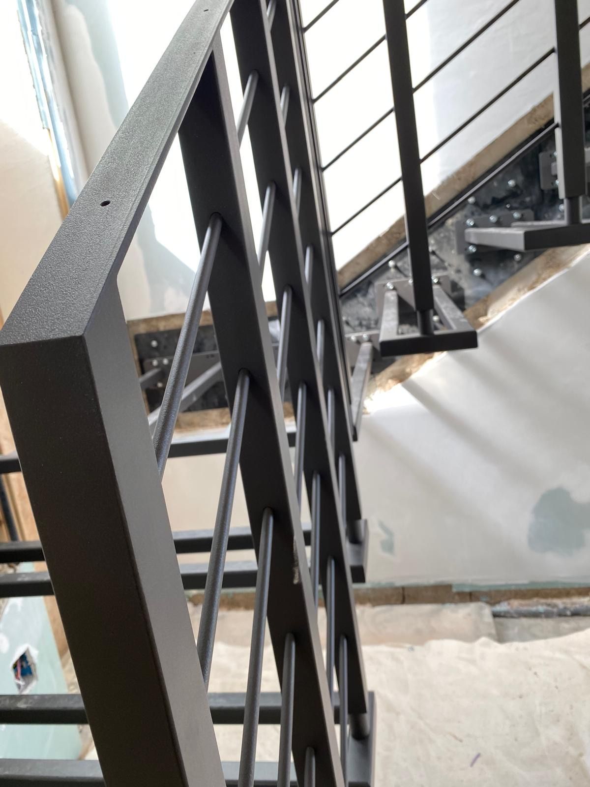 Ringhiera per scale in metallo nero con supporti diagonali, installata in un vano scale.