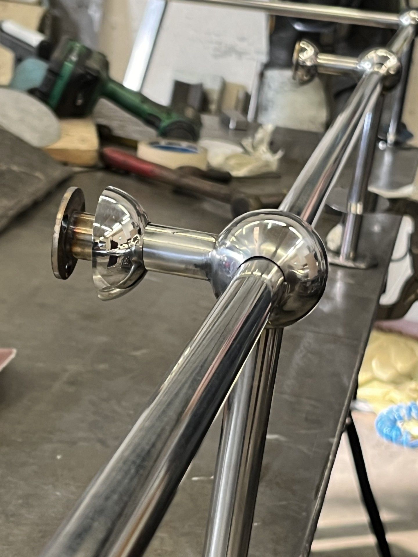 Assemblaggio di tubi metallici cromati con giunto rotondo e morsetto su un banco da lavoro, sfondo officina