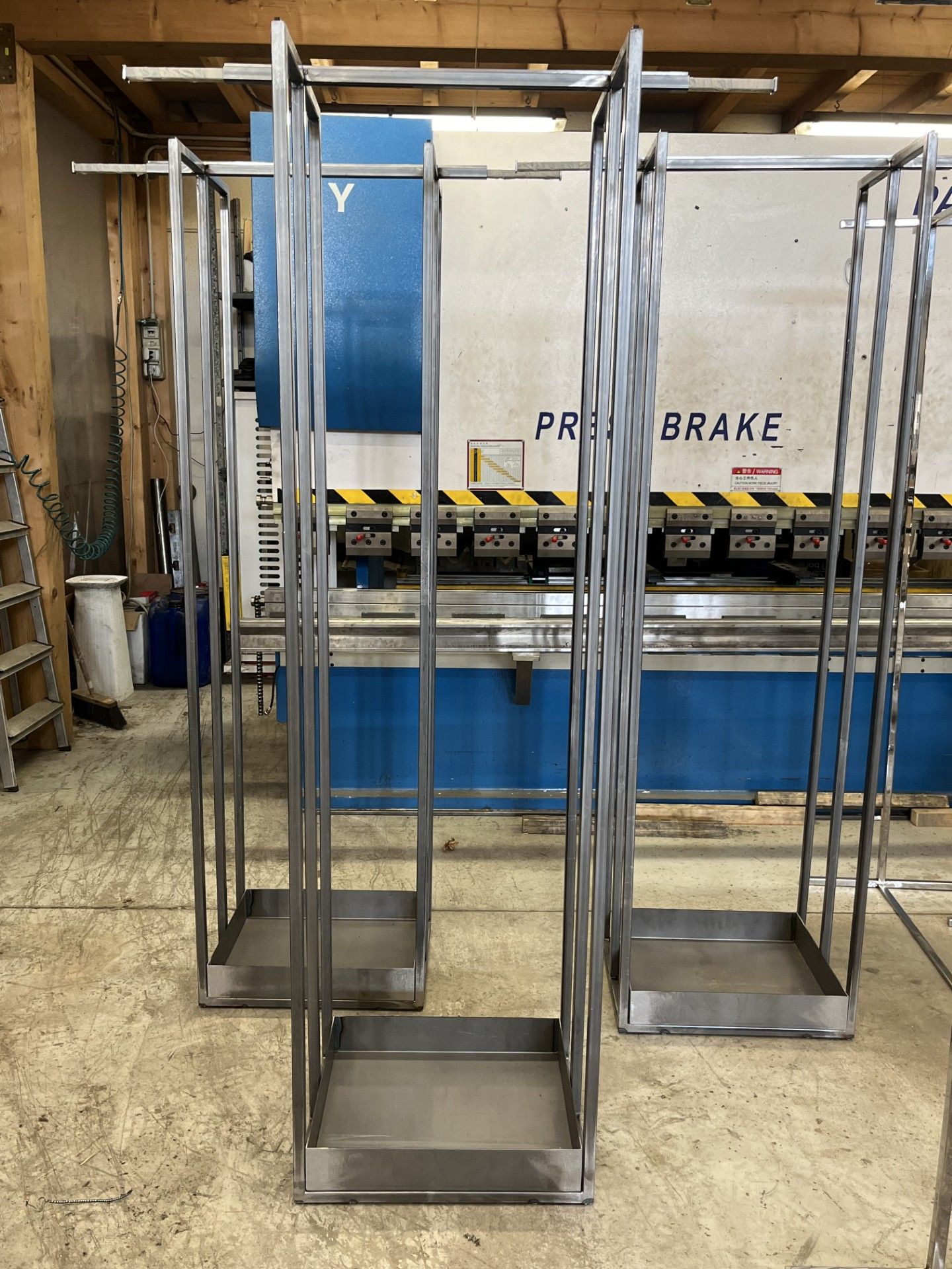 Scaffalature metalliche alte in un magazzino con macchinari blu sullo sfondo.
