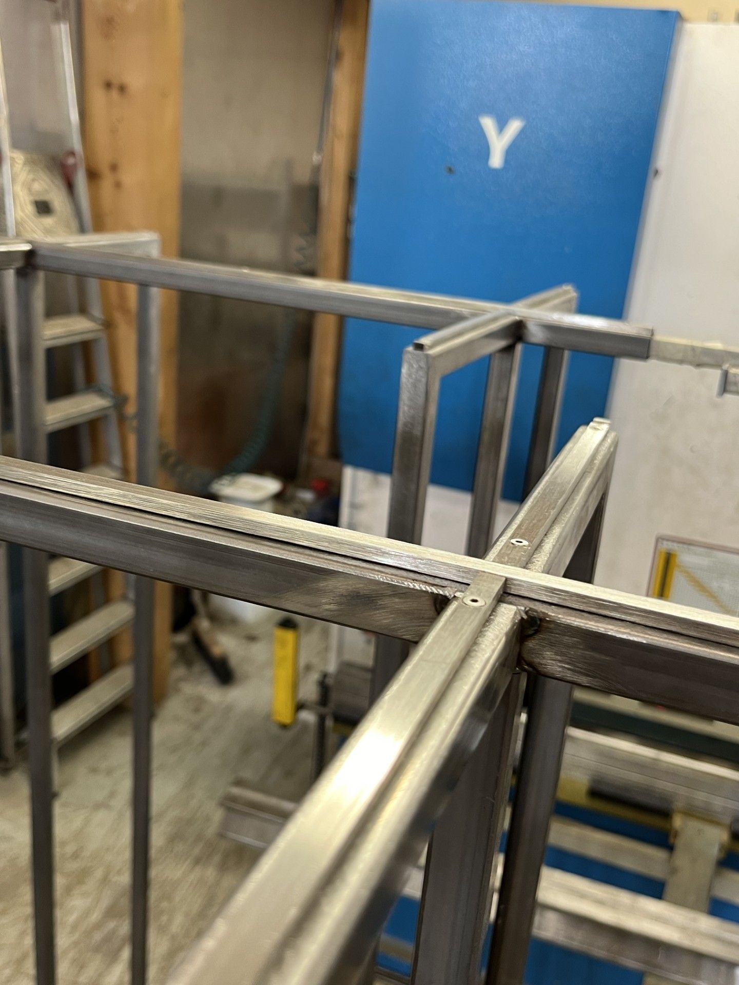 Struttura metallica in un'officina, con porta blu e scala sullo sfondo.