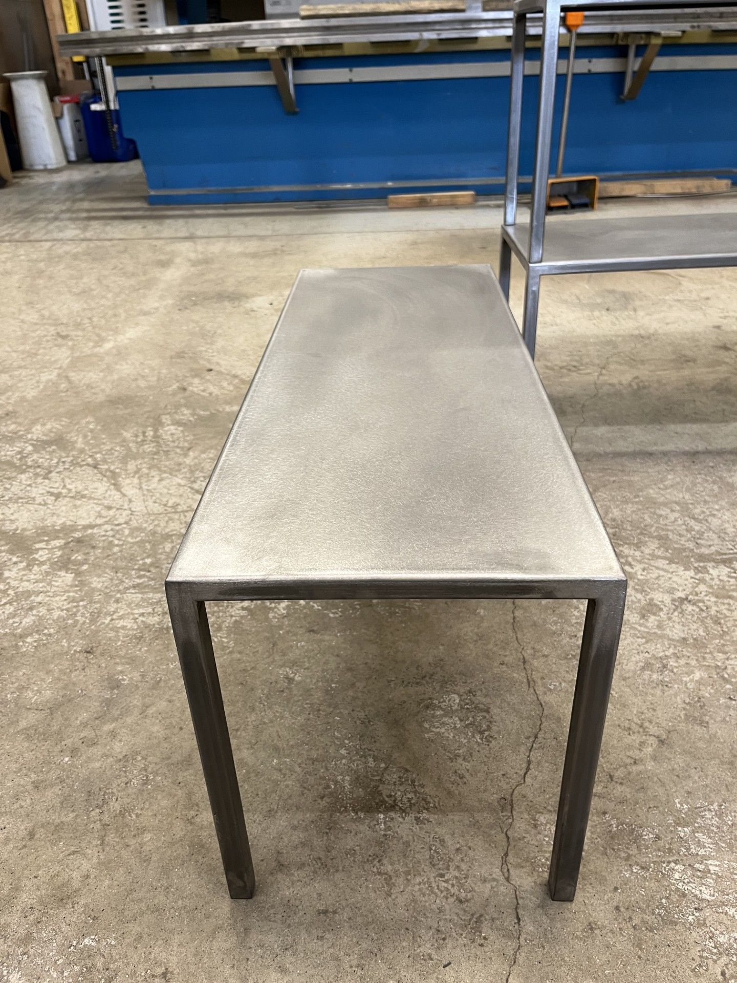 Tavolo rettangolare in metallo grigio in un'officina industriale, visto dall'alto.