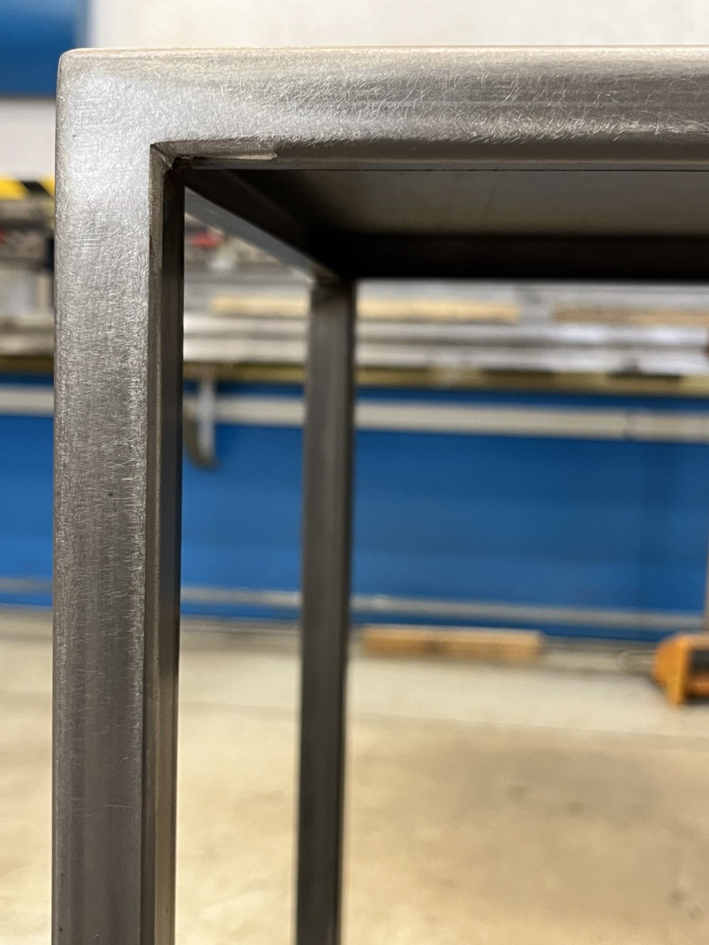 Primo piano dell'angolo di una cornice metallica grigia con uno sfondo sfocato di un'officina.