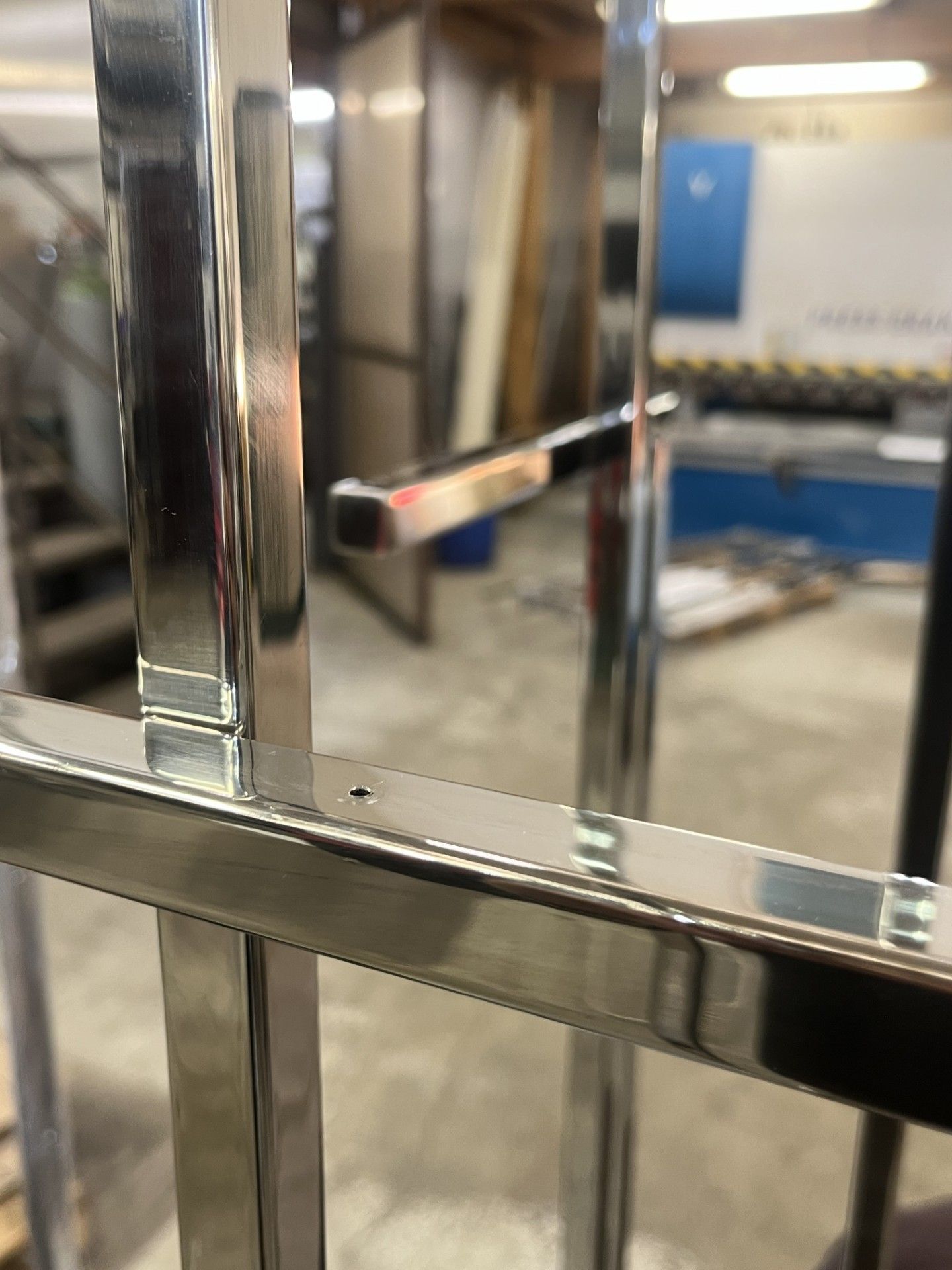 Primo piano di una ringhiera o di un telaio per carrello in metallo cromato lucido all'interno di un'officina.