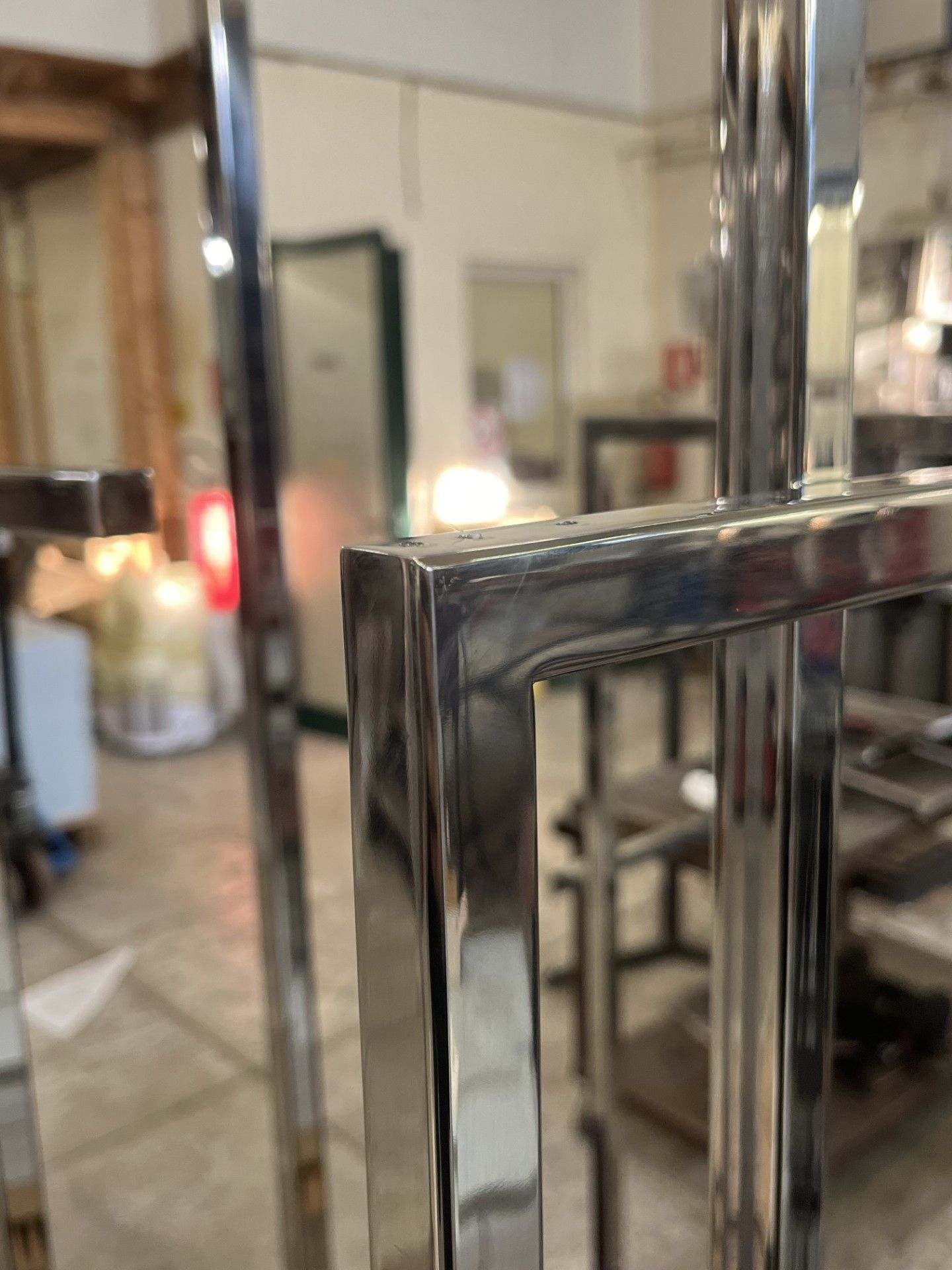 Schienali di sedie cromate in un caffè con tavolini sfocati e una calda illuminazione interna.