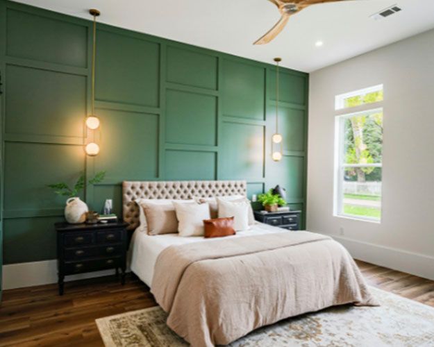 Modern bedroom with sage green paneled walls, a tufted bed, dark nightstands, and a bright window.