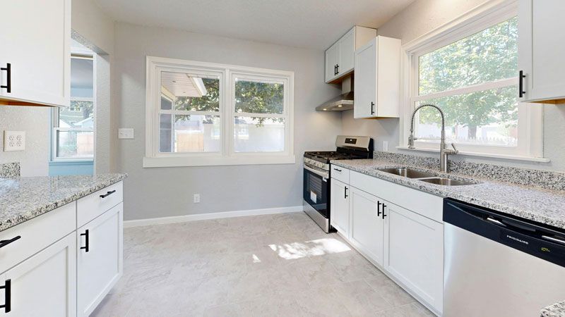 Bright modern kitchen with white cabinets, granite counters, and a large window over the sink