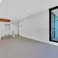 Empty modern room with white walls, beige floor, recessed lights, and a large glass door