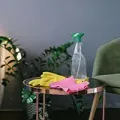 Cleaning supplies on a glass table beside a green chair, with yellow gloves and pink cloths.