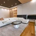 Modern living room with white sectional sofa, round coffee table, wood floor, and recessed ceiling lights