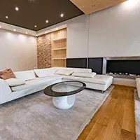 Modern living room with white sectional sofa, round coffee table, wood floor, and recessed ceiling lights