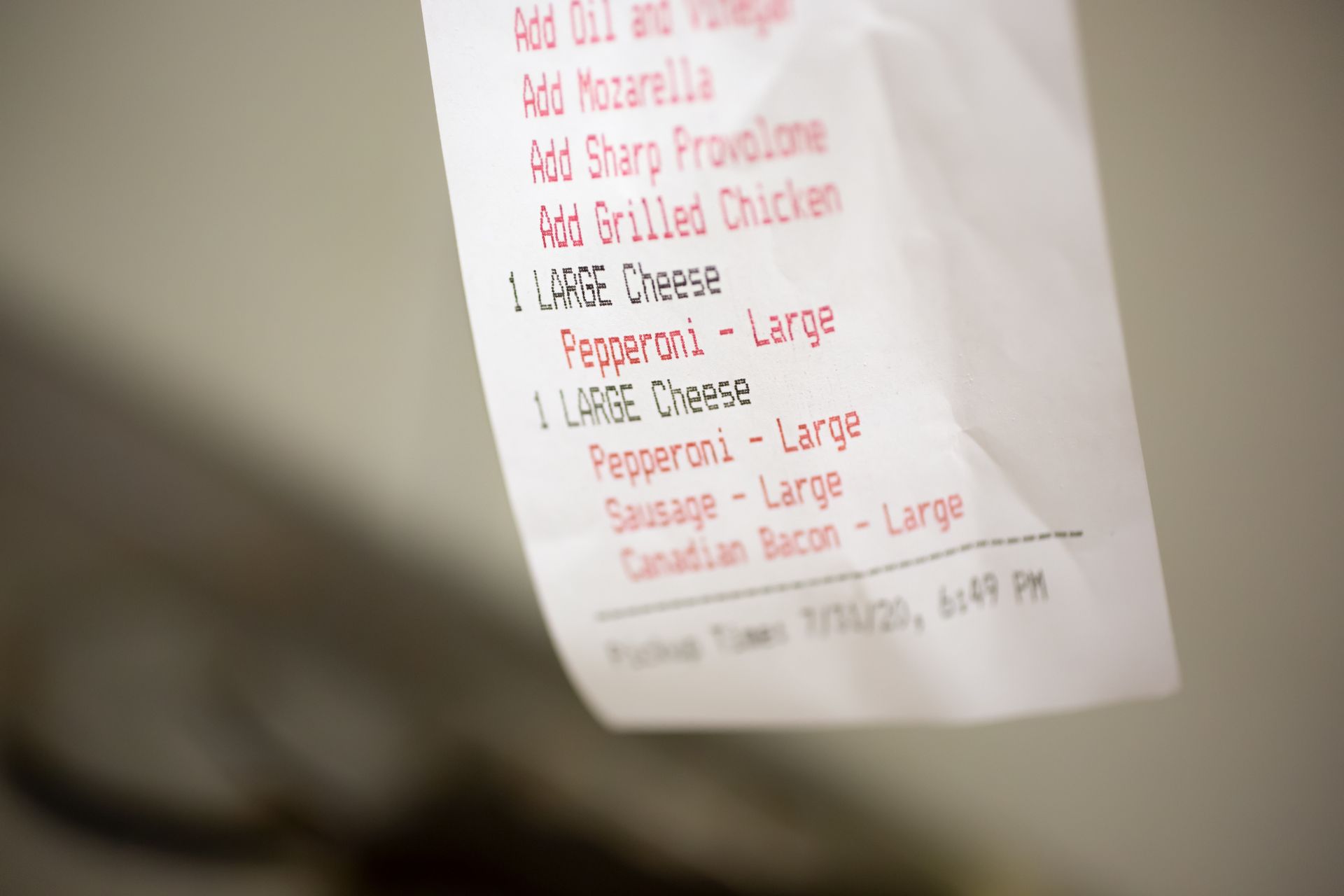 White menu note with red handwritten food options, taped to a wall.