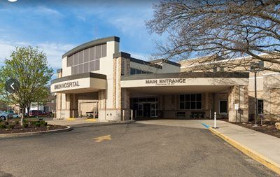 Hospital entrance with covered driveway and beige stone facade on a clear day