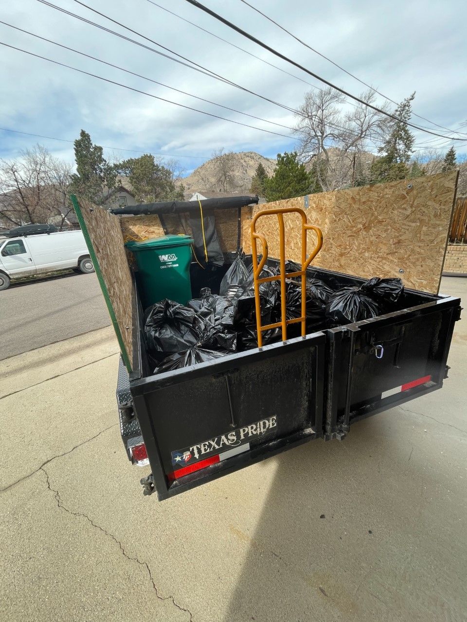 dark blue dumpster in front of a white residential garage