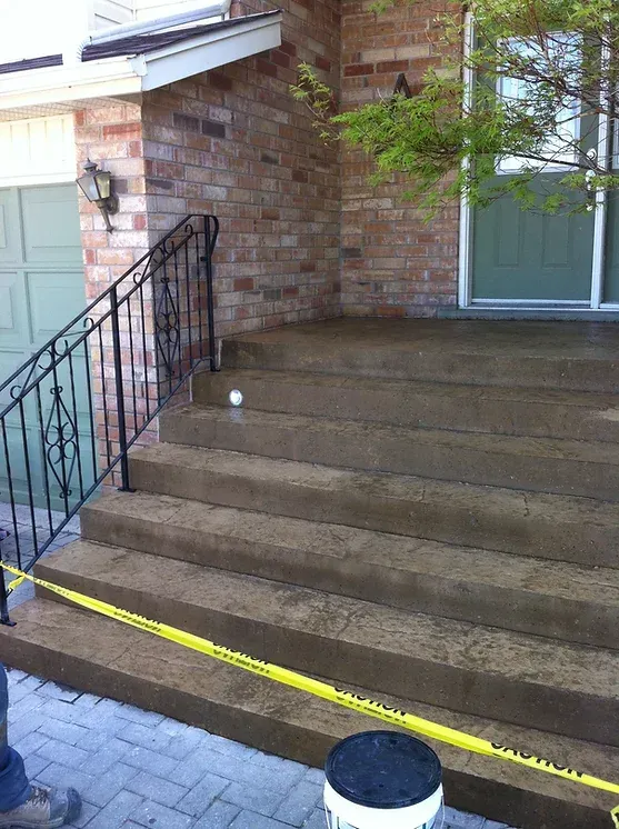 A bucket is sitting on the steps of a brick house.