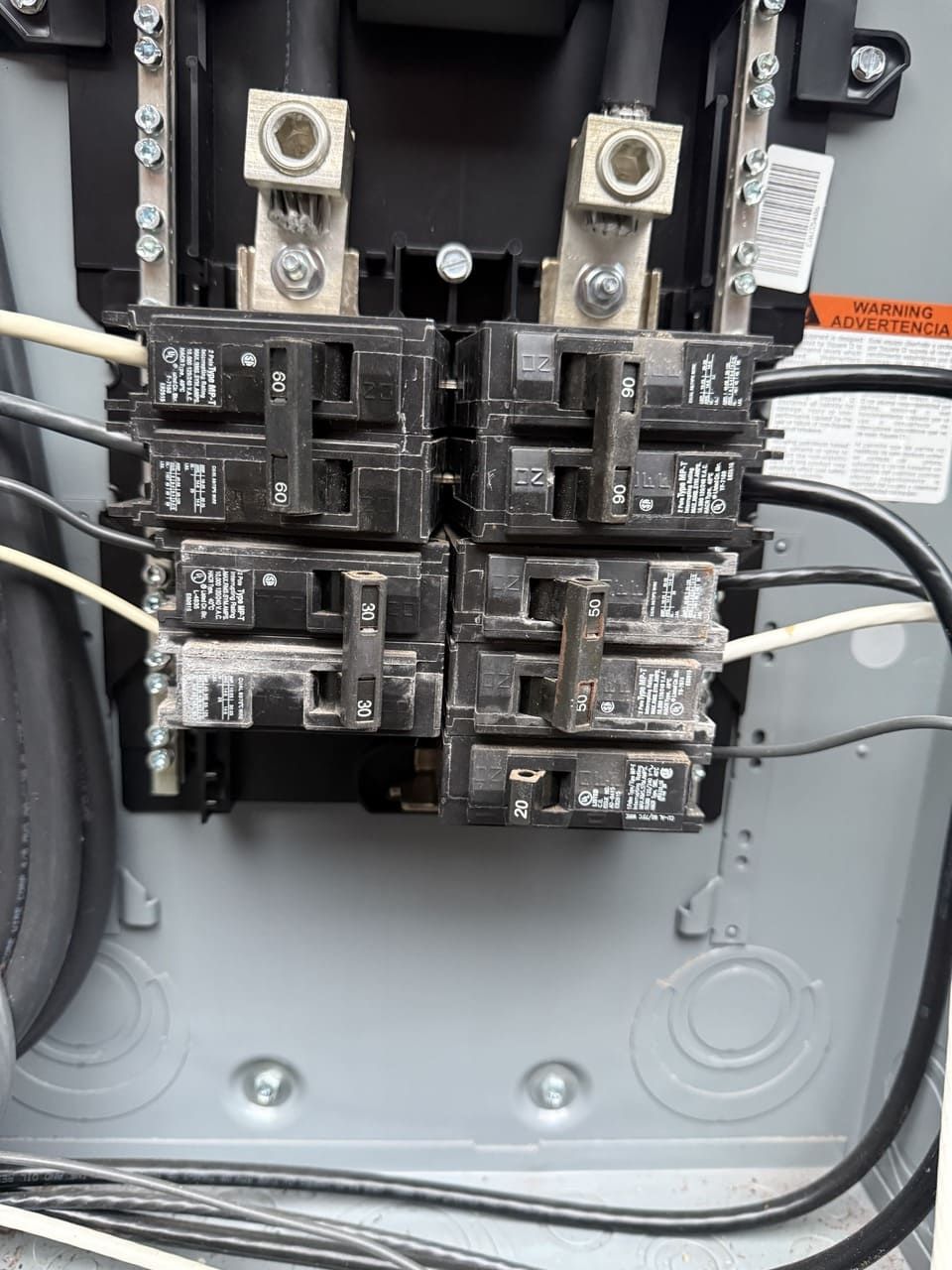 An open electrical service panel showing multiple circuit breakers with connected black and white wiring.