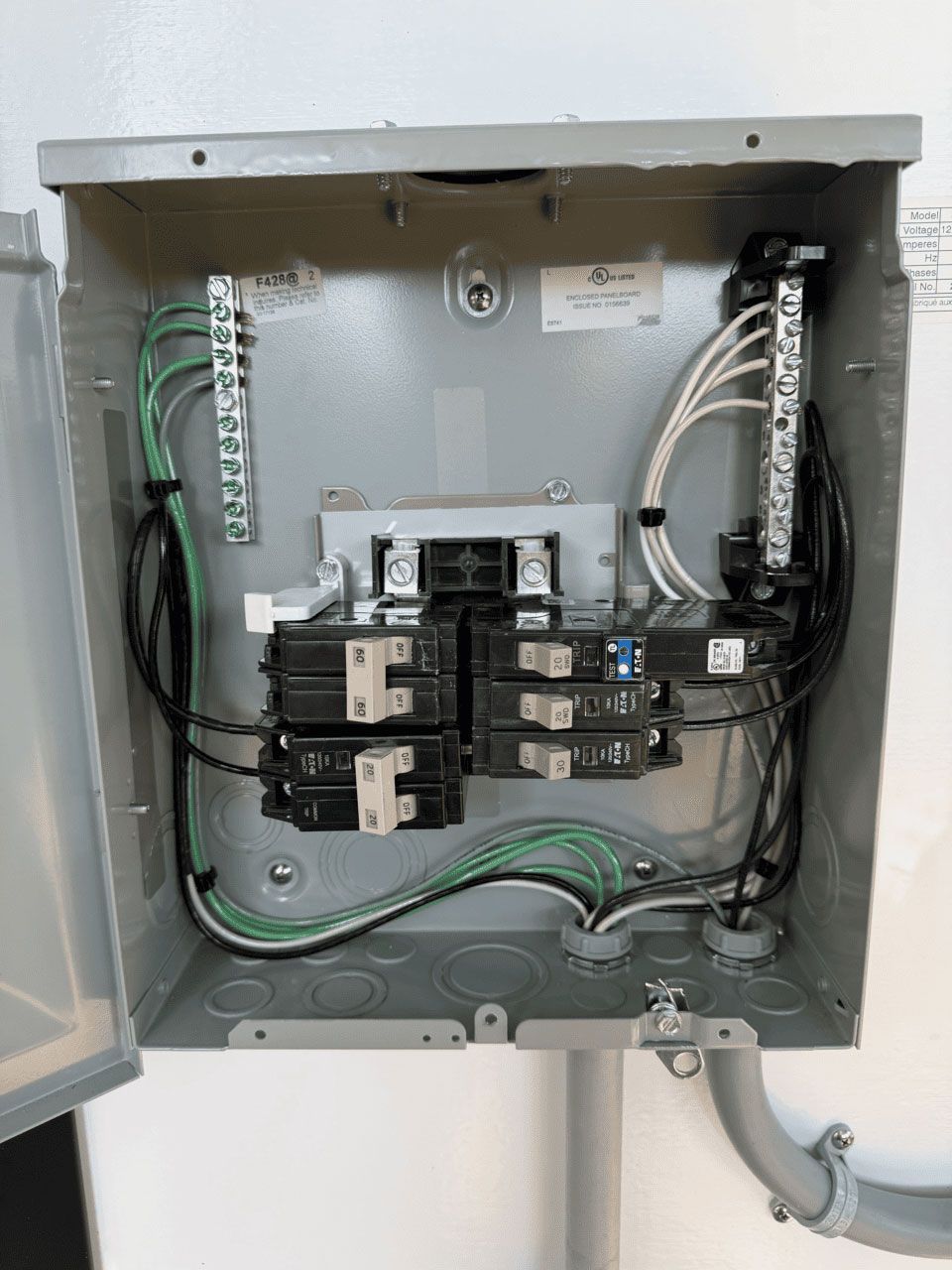 Open electrical breaker panel with installed breakers and wiring, featuring a ground bar on the left and neutral on the right.