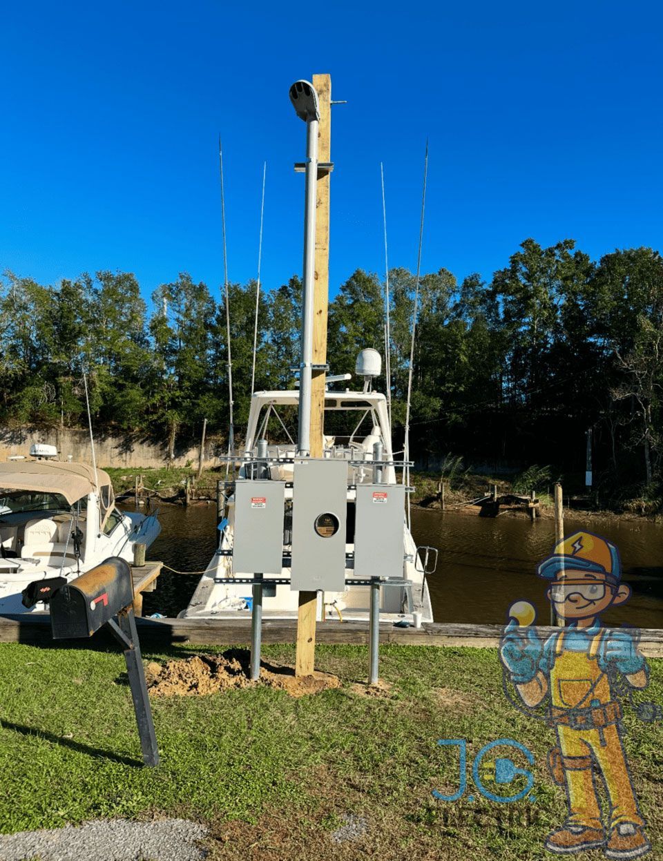 A utility pole with electrical boxes stands near a dock where a boat is moored. A cartoon mascot is in the lower right.