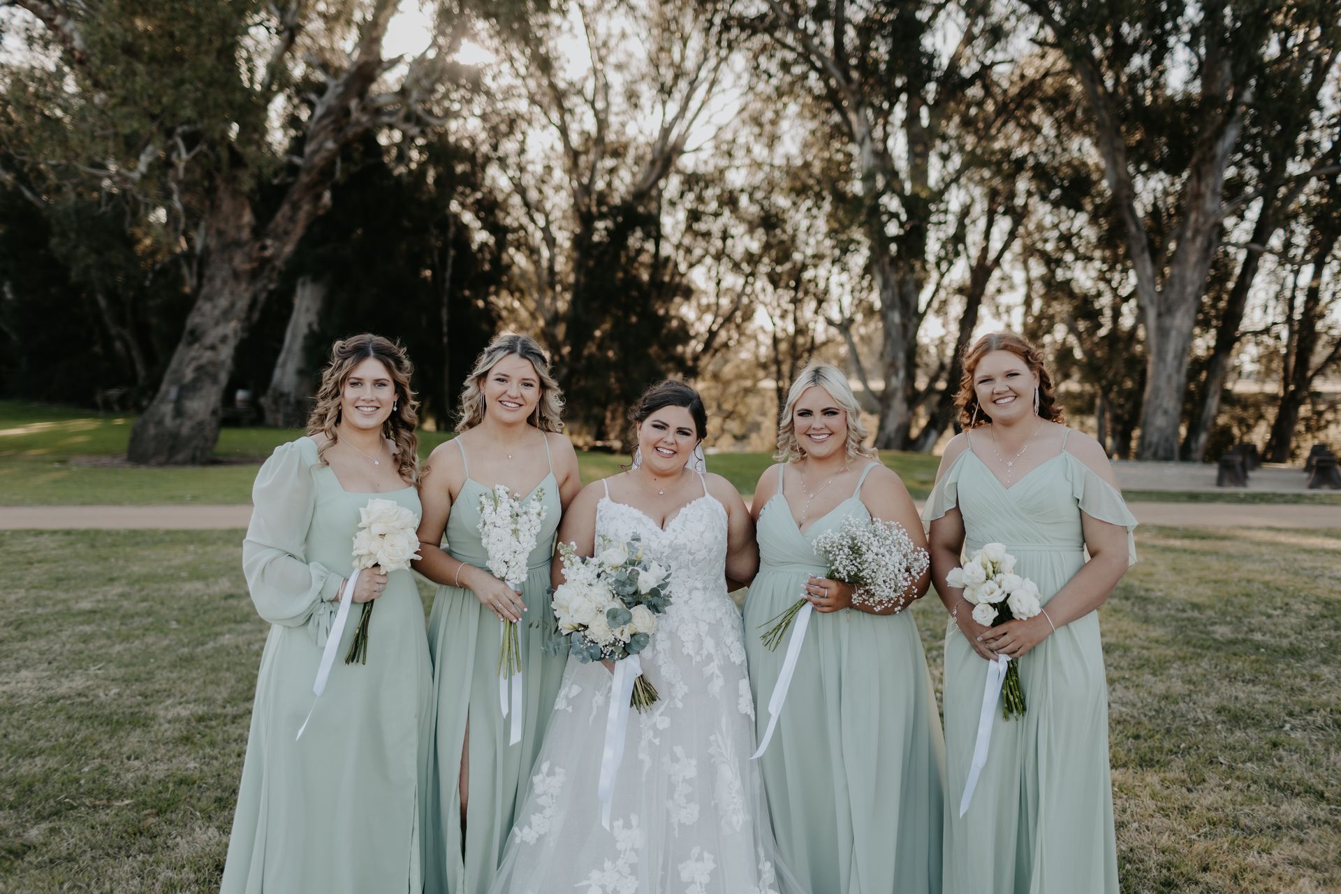 Bride with Bridesmaids in Green Dresses Holding Bouquets Outdoors — Denise's Flower Studio In Dubbo, NSW