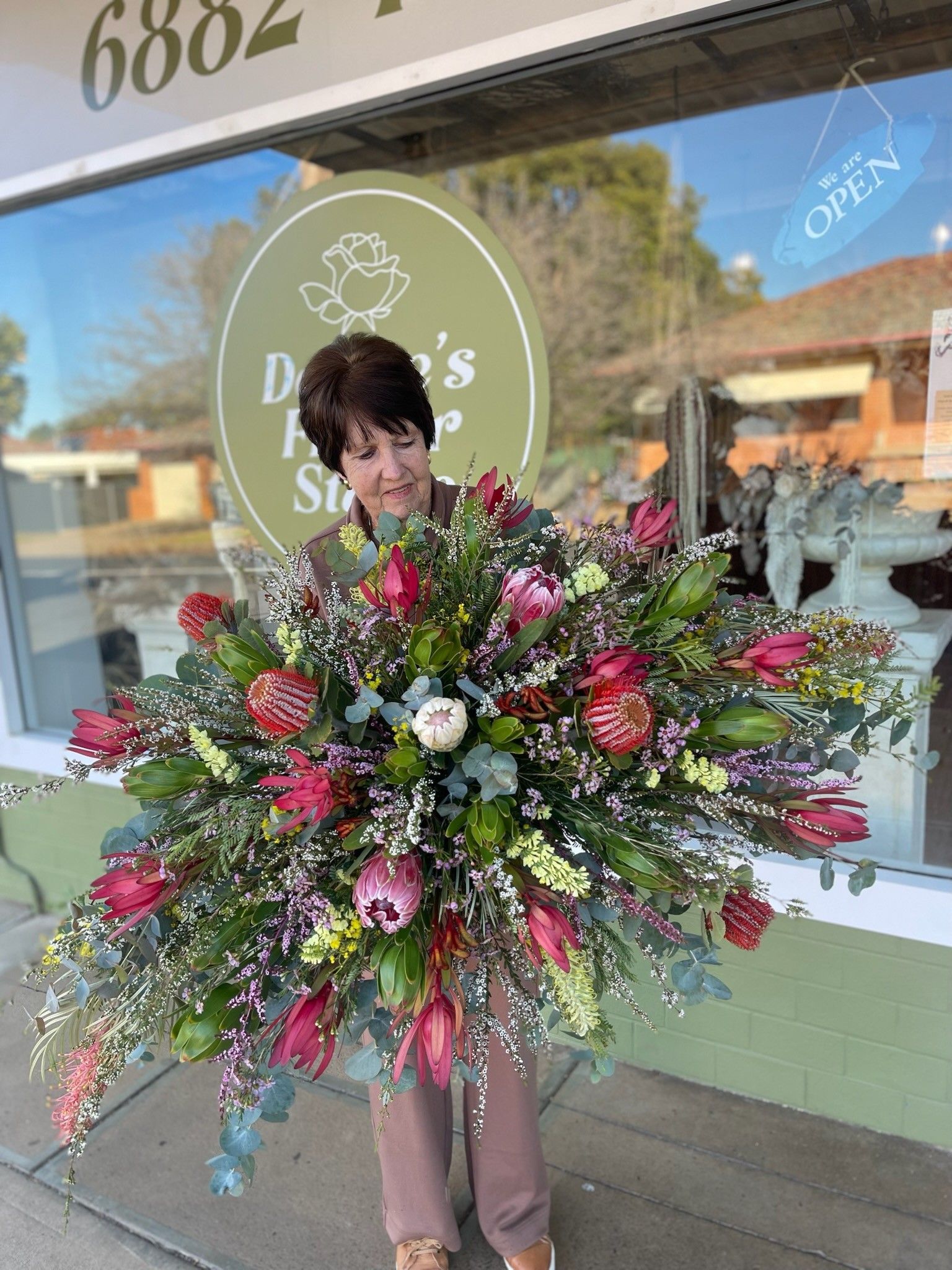 Woman Holding Large Floral Arrangement Outside a Flower Shop — Denise's Flower Studio In Dubbo, NSW