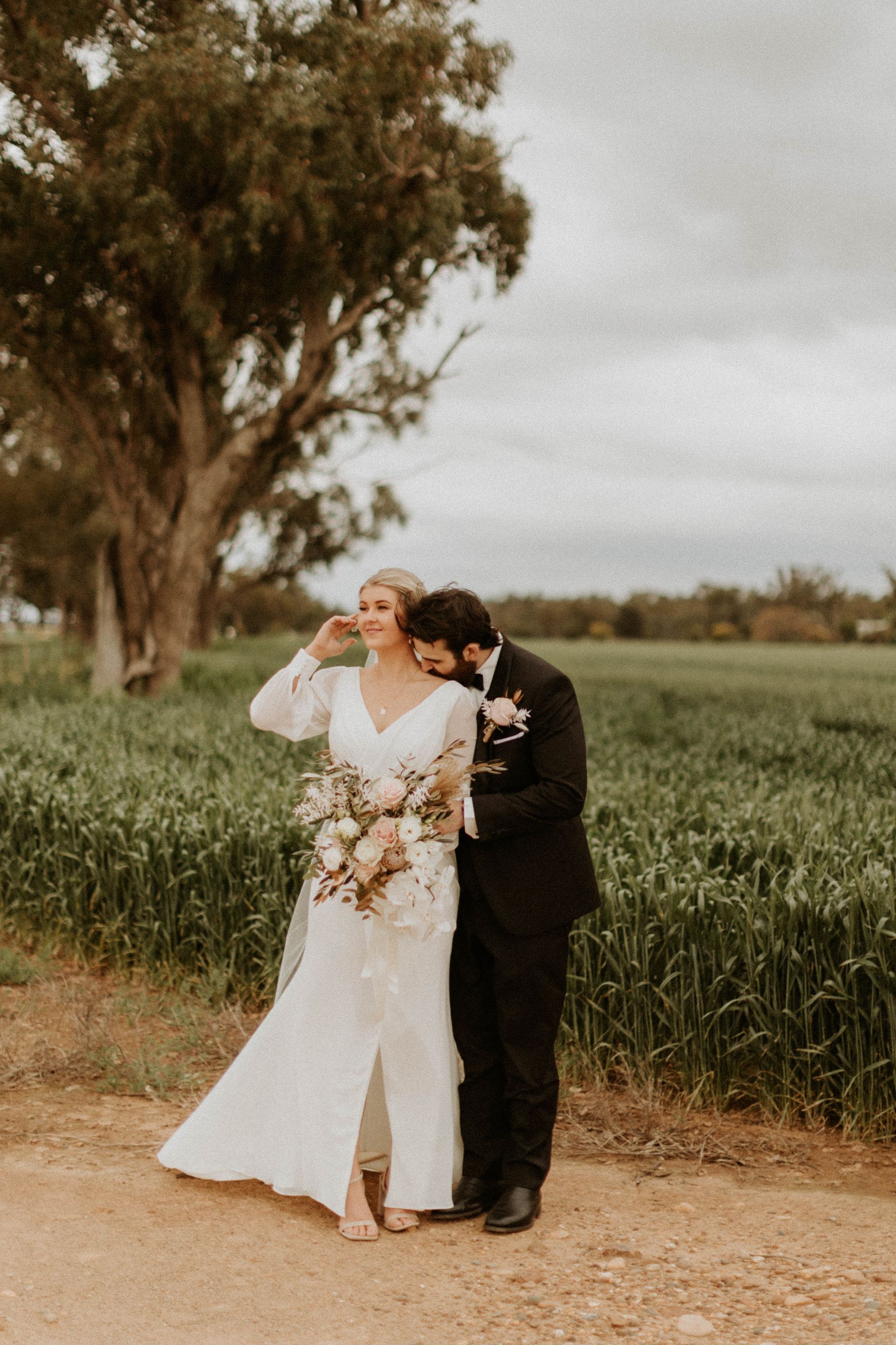 Bride and Groom Embracing in A Field — Denise's Flower Studio In Dubbo, NSW