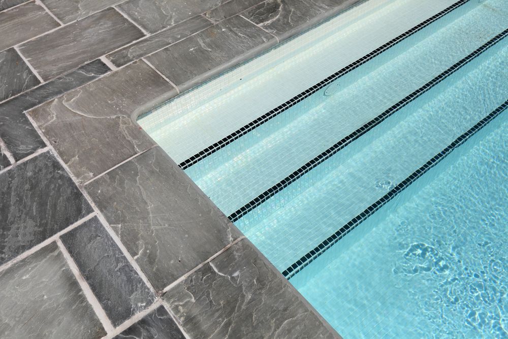 A Swimming Pool With Steps Leading to It and a Tiled Floor — NQ Tropical Pools & Renovations in Cranbrook, QLD