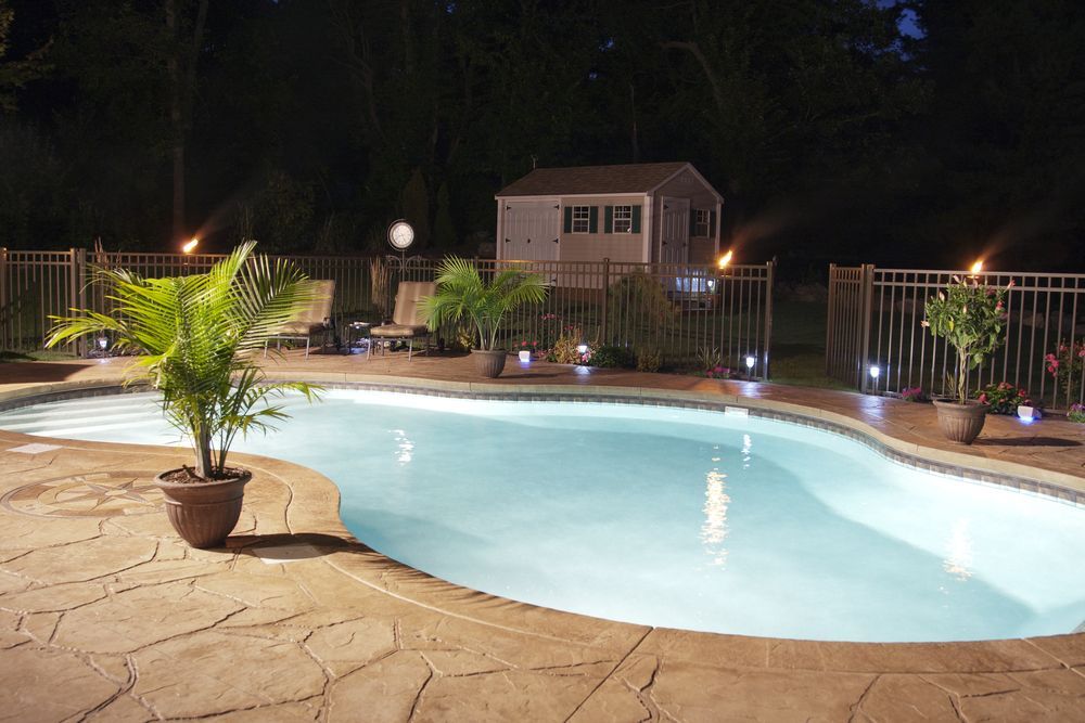 A Large Swimming Pool is Lit Up at Night — NQ Tropical Pools & Renovations in Cranbrook, QLD