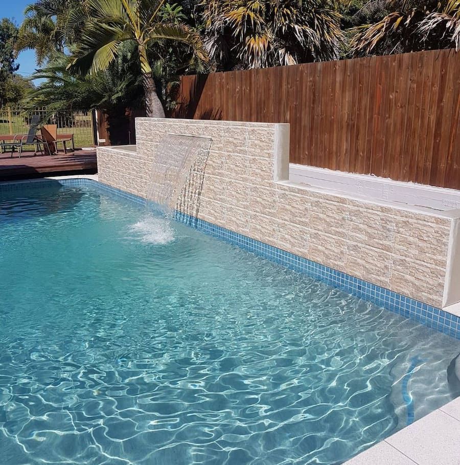 A Swimming Pool With a Waterfall on the Side of It — NQ Tropical Pools & Renovations in Cranbrook, QLD