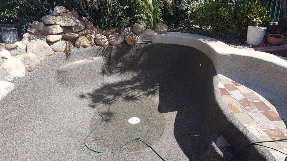 A Swimming Pool With a Green Hose Attached to It — NQ Tropical Pools & Renovations in Cranbrook, QLD