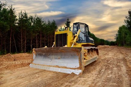 A bulldozer is driving down a dirt road.