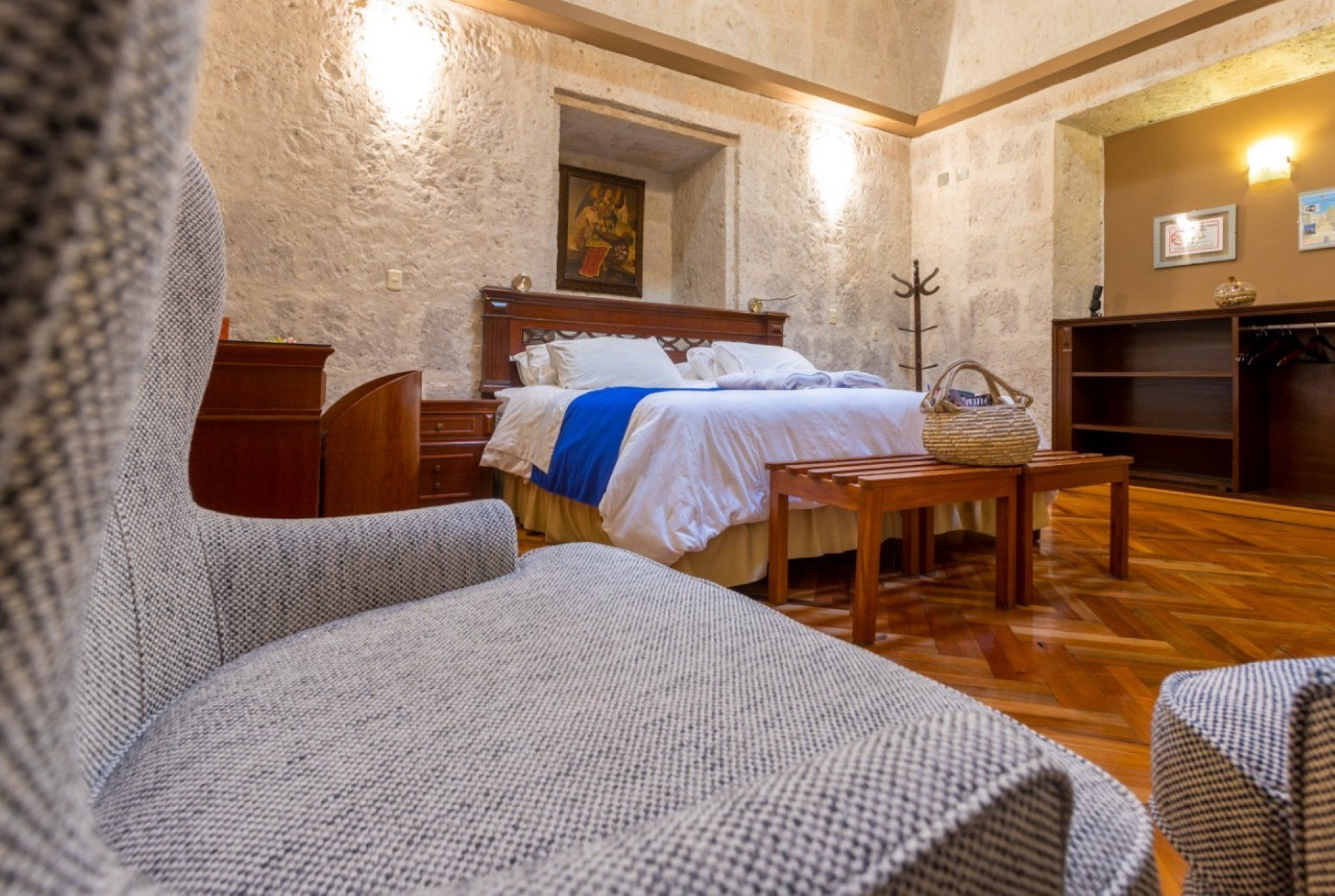 Cozy bedroom with textured chairs, wooden floor, king bed, and warm beige walls