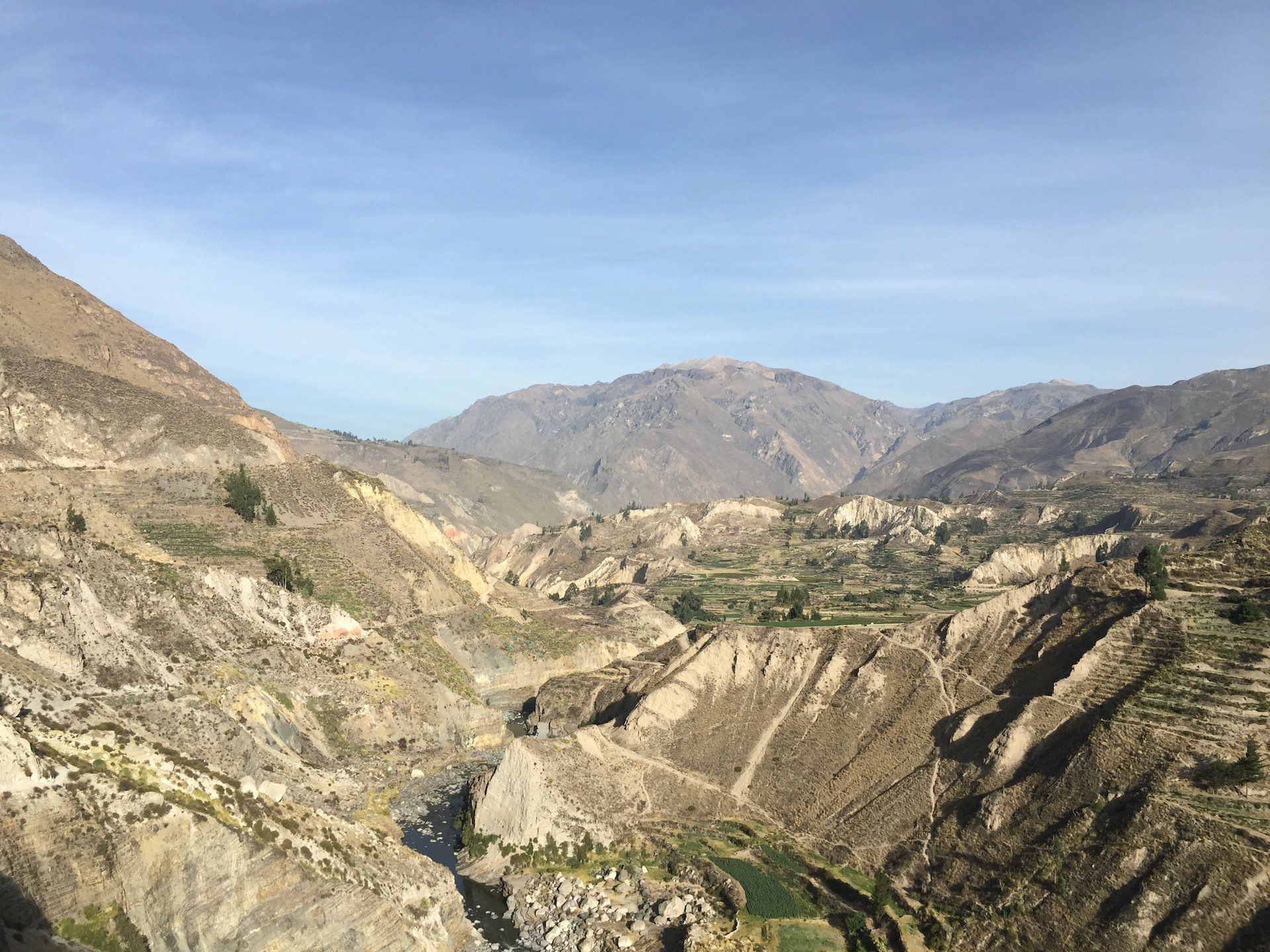 Arid mountain valley with rugged tan slopes under a clear blue sky