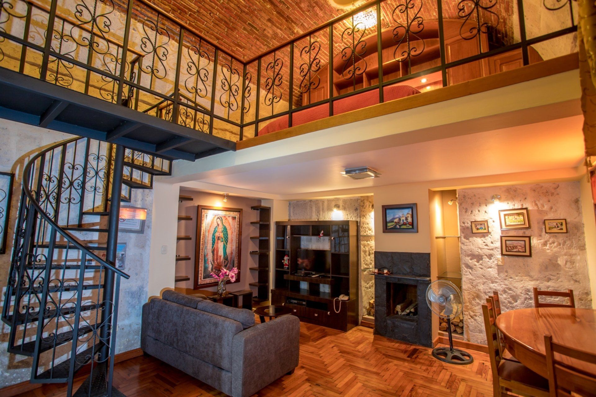 Loft-style living room with spiral staircase, wrought-iron railing, sofa, and warm lighting