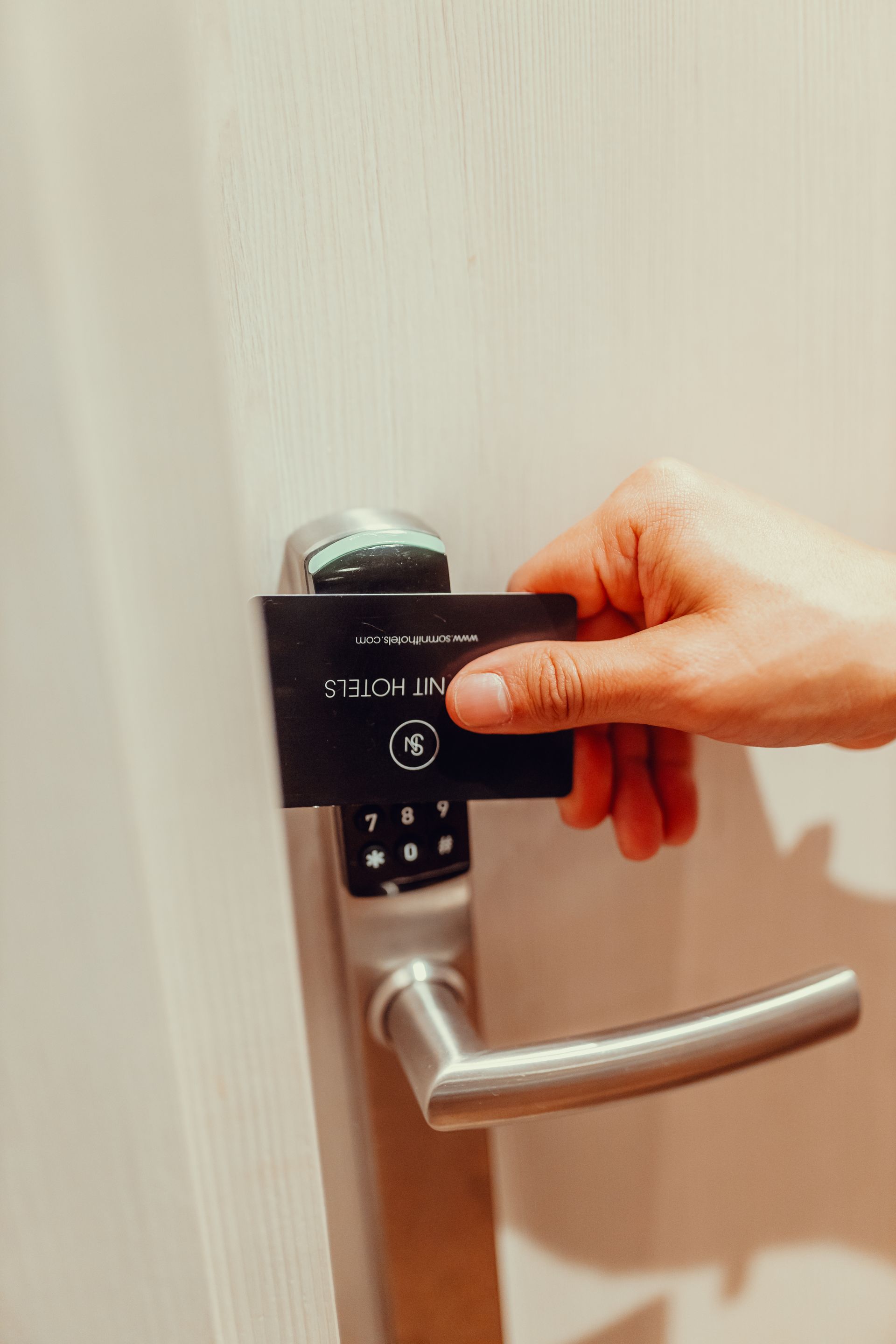 Manija de puerta de habitación de hotel girando a mano con cerradura de teclado digital en una puerta blanca.