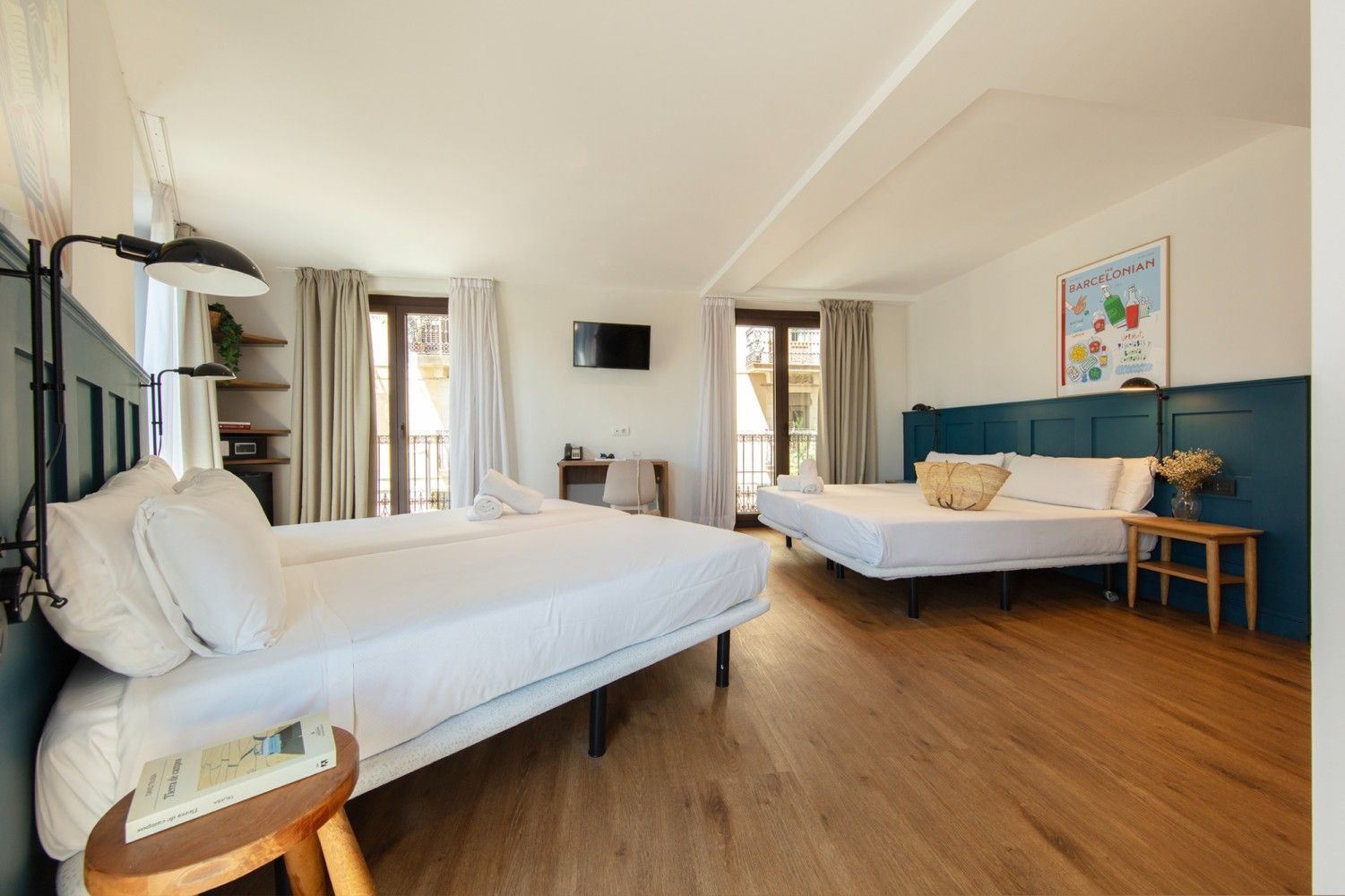 Una luminosa habitación de hotel con dos camas, paredes revestidas de paneles azules, pisos de madera.
