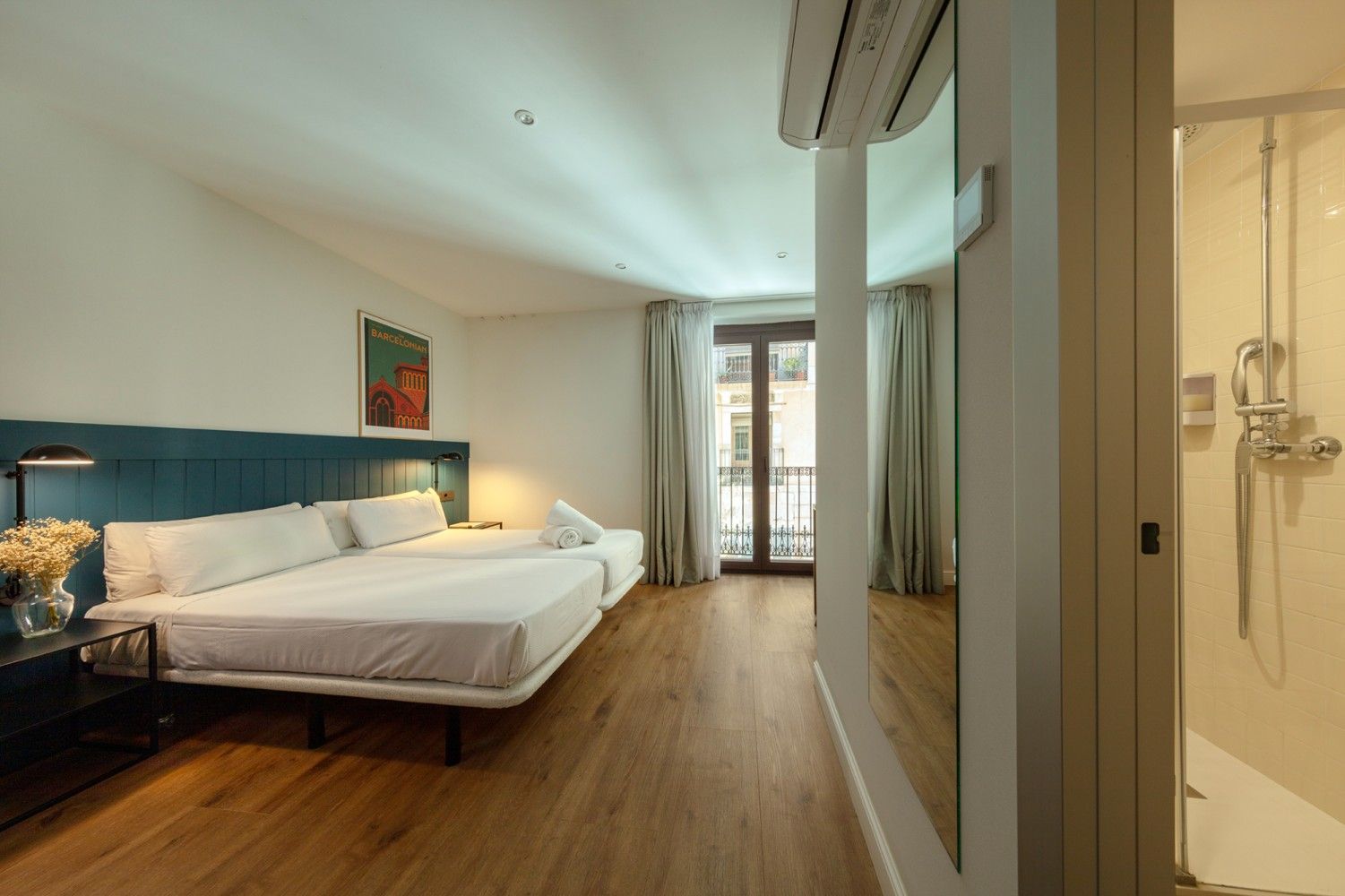 Una moderna habitación de hotel con dos camas individuales sobre una cabecera azul, suelos de madera.