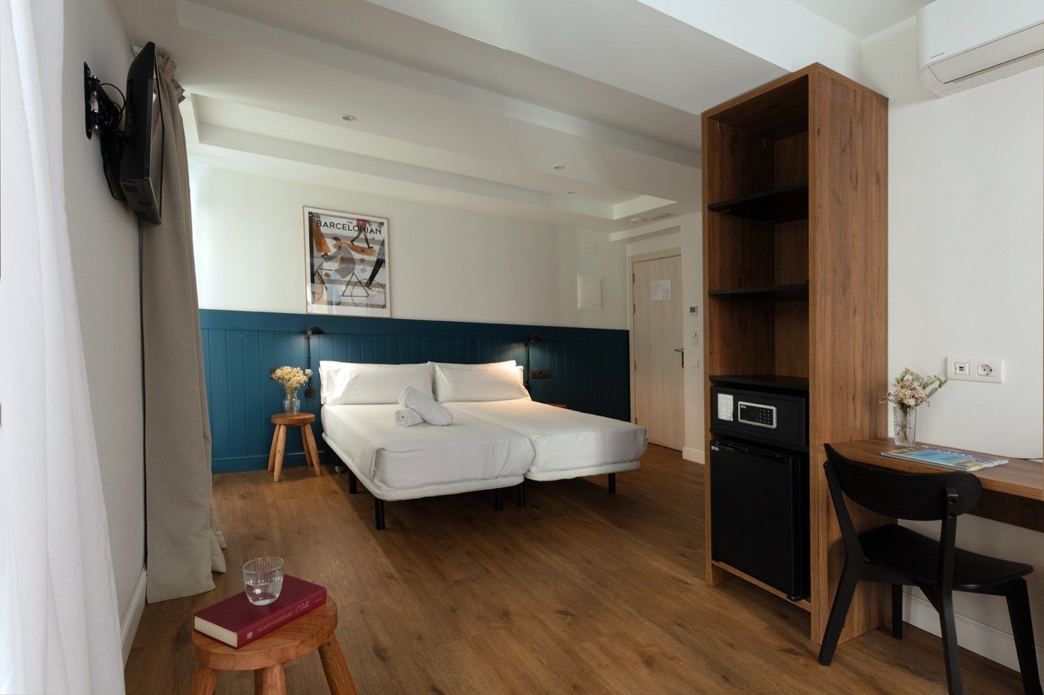 Apartamento tipo estudio minimalista con cama, suelo de madera, escritorio y estantería frente a una pared .