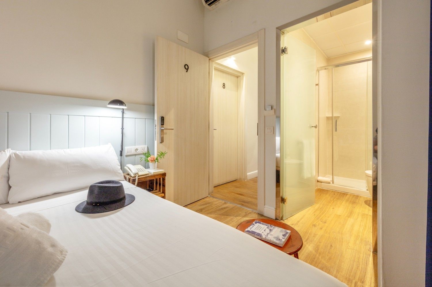 Un dormitorio con una cama rematada con un sombrero, junto a un baño abierto con paredes de cristal.