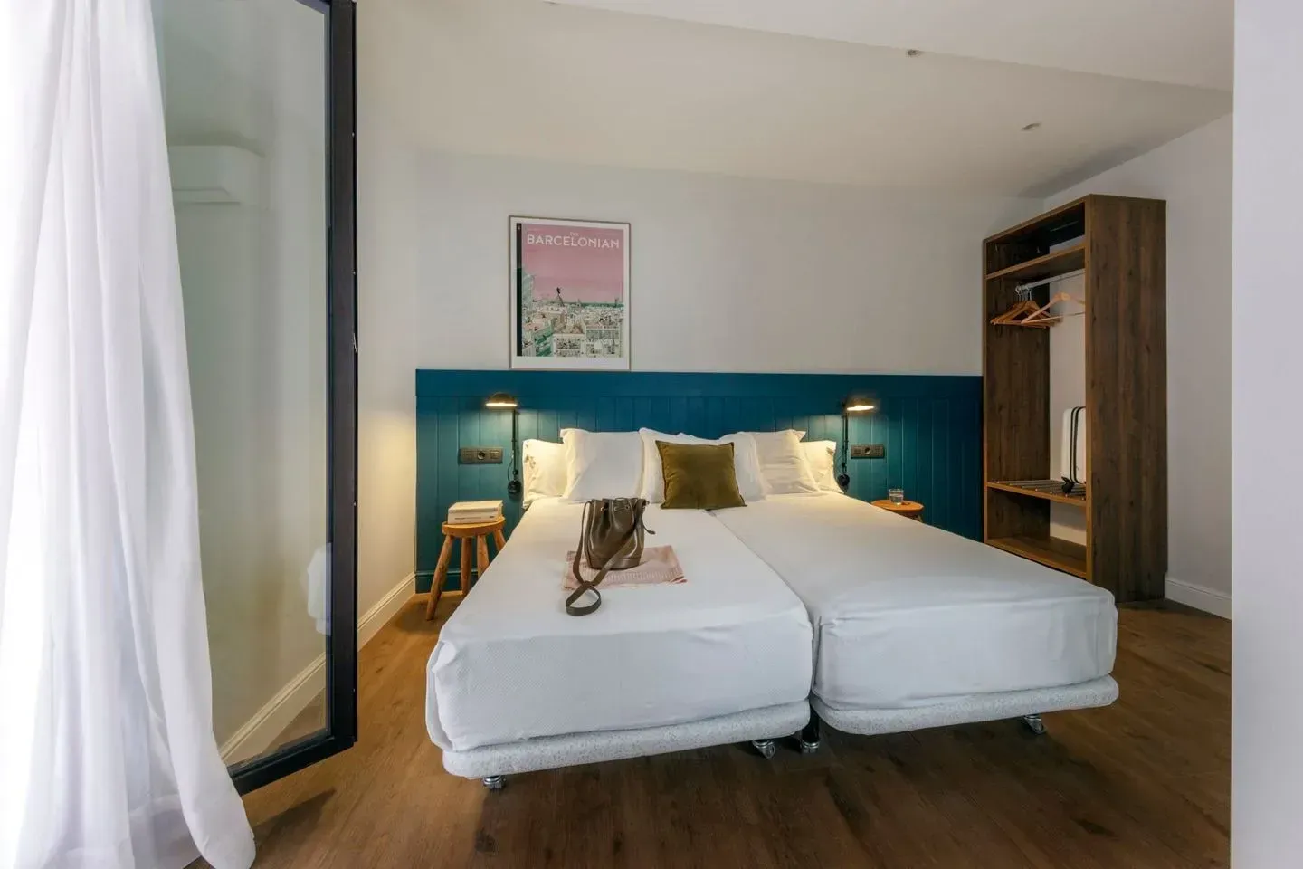 Dormitorio de hotel moderno con dos camas individuales juntas, cabecera color verde azulado.