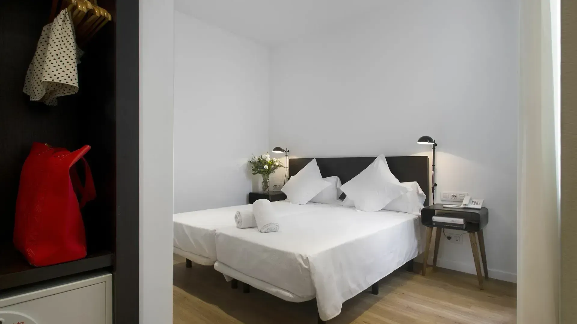 Una moderna habitación de hotel con dos camas individuales blancas, mesitas de noche con lámparas a juego.