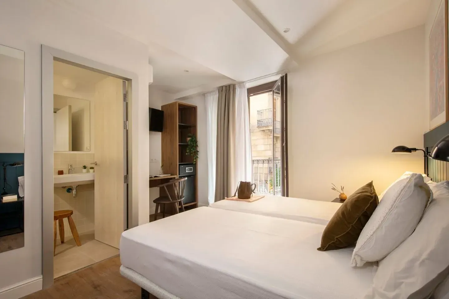 Una habitación de hotel moderna y bien iluminada que cuenta con una cama blanca con almohadas,.