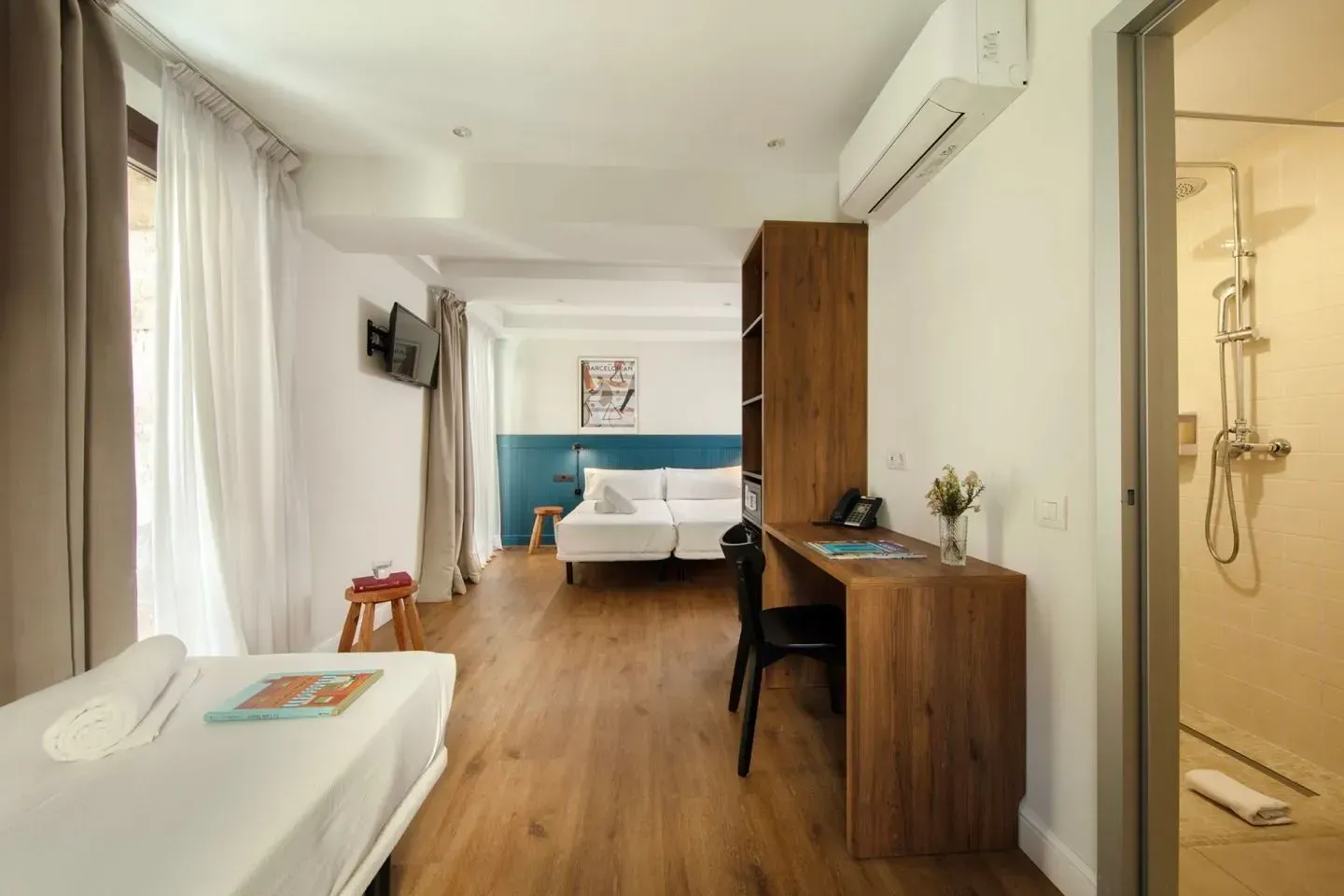 Una habitación de hotel con una cama individual en primer plano, un escritorio con una silla.