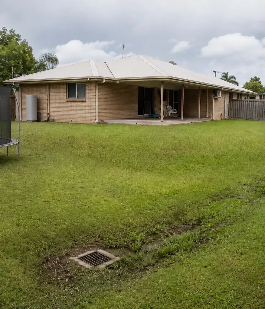 A grated drainage pit with a swale used to direct water to the drain in this sloped backyard in Elliott Heads.