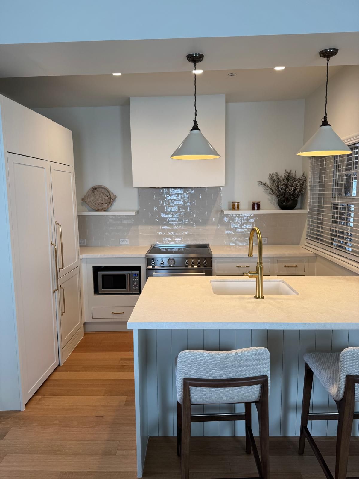 Modern kitchen with white cabinets, light wood floor, and island with stools.