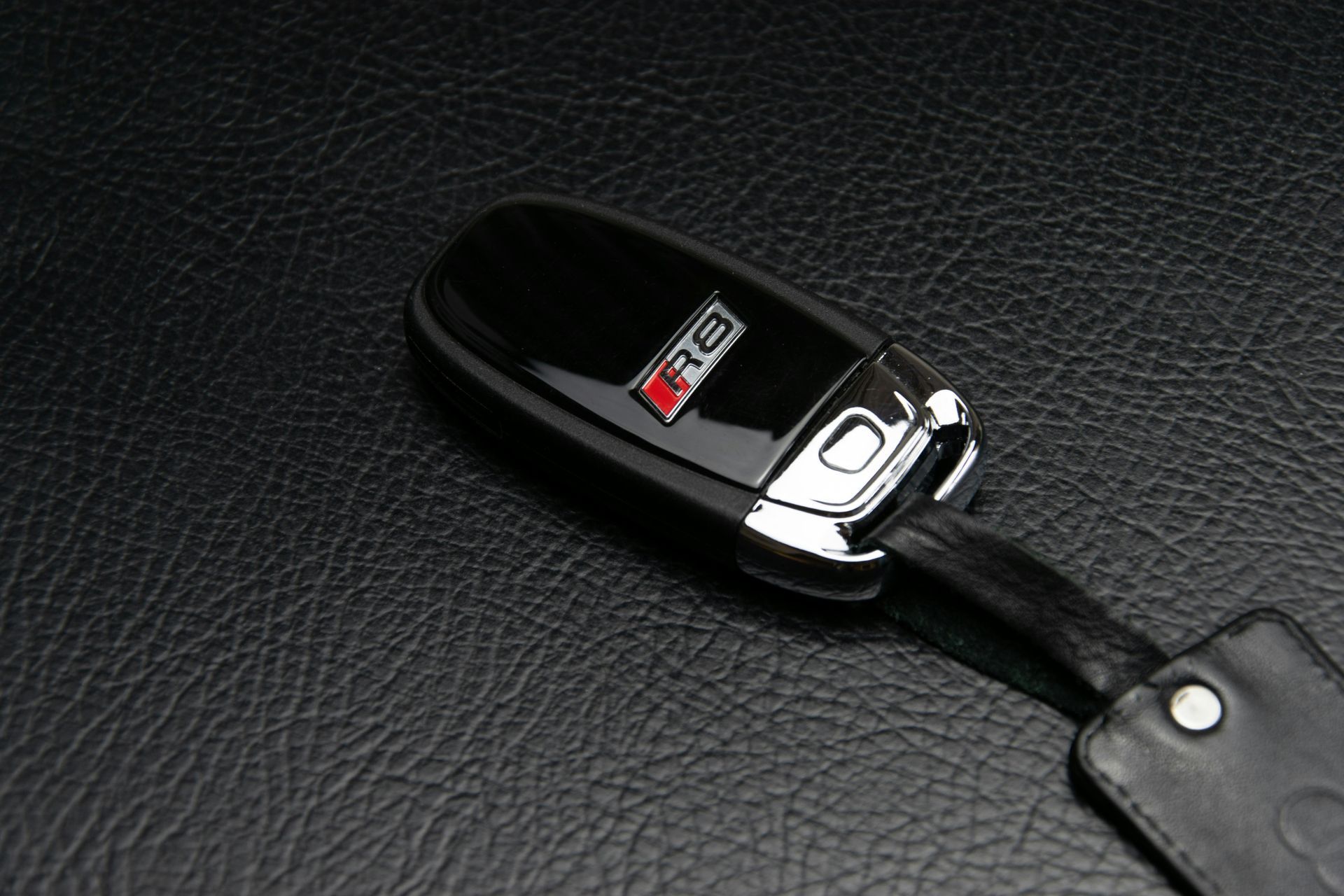 Black Audi R8 car key on a textured black surface.