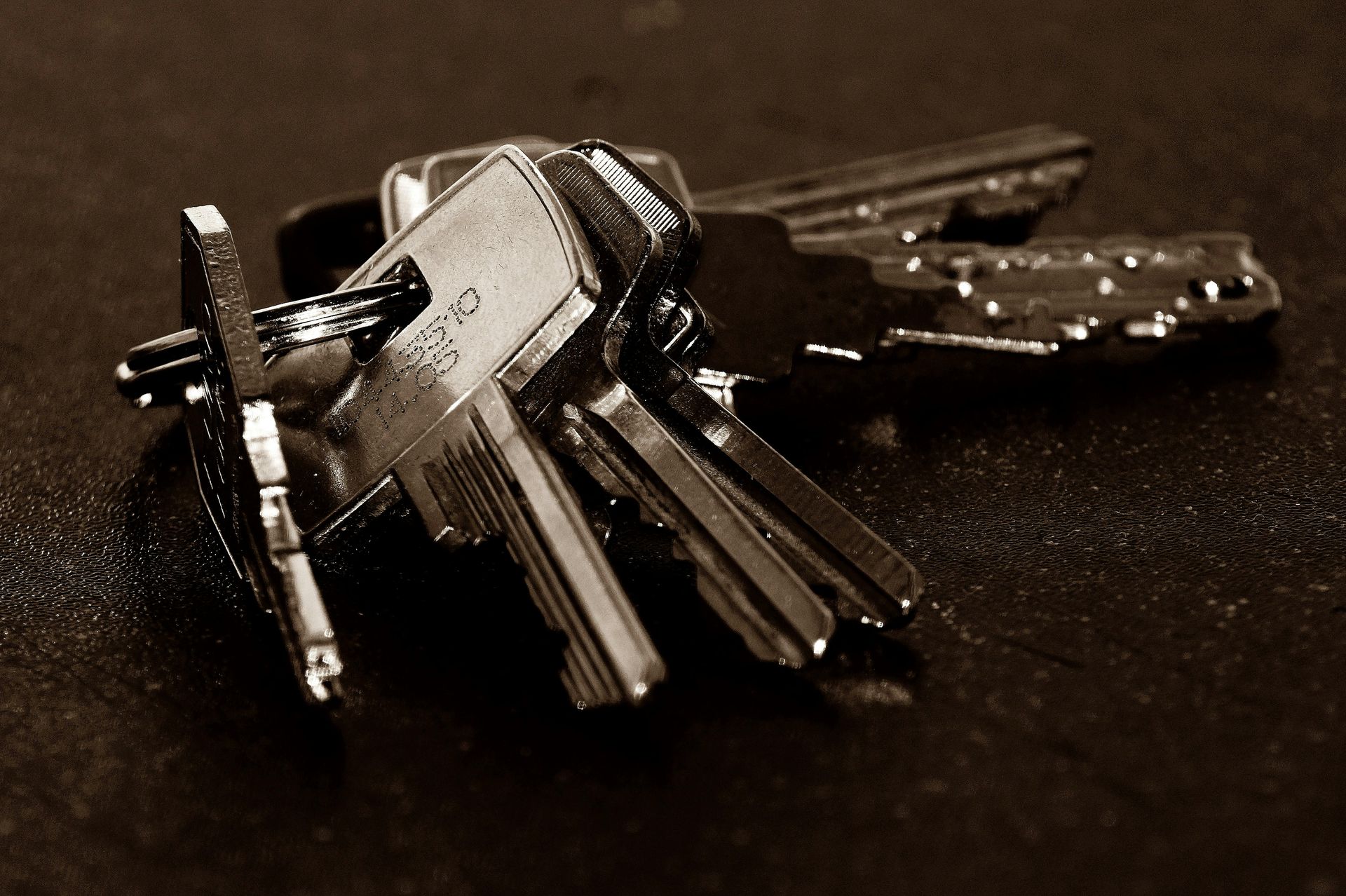 A keyring with several metal keys on a dark surface.