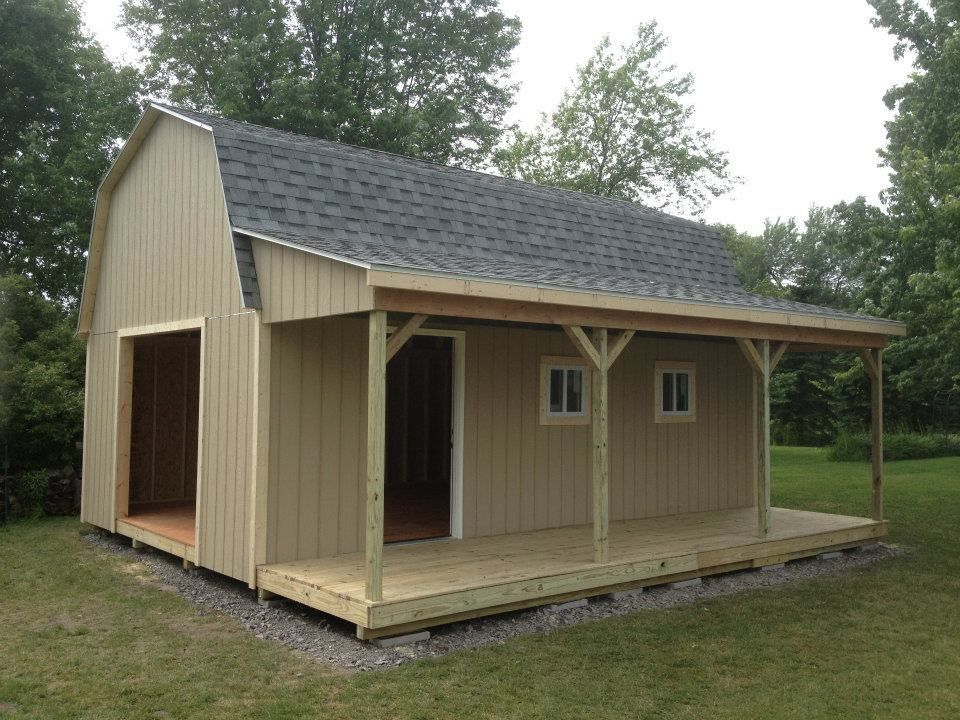 Tan shed with a porch and gray roof, built on gravel, with an open door.