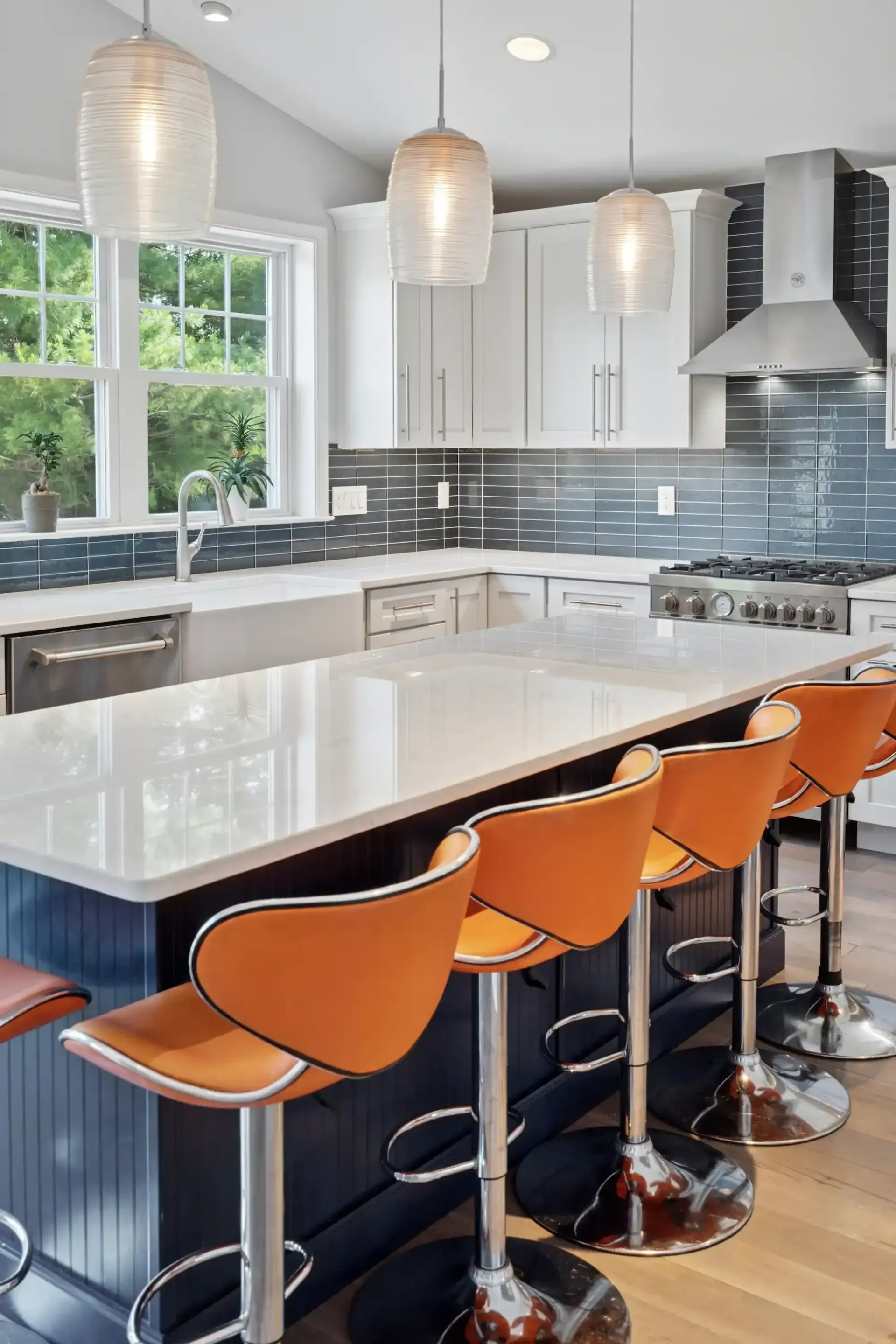 A kitchen with a large island and orange bar stools.