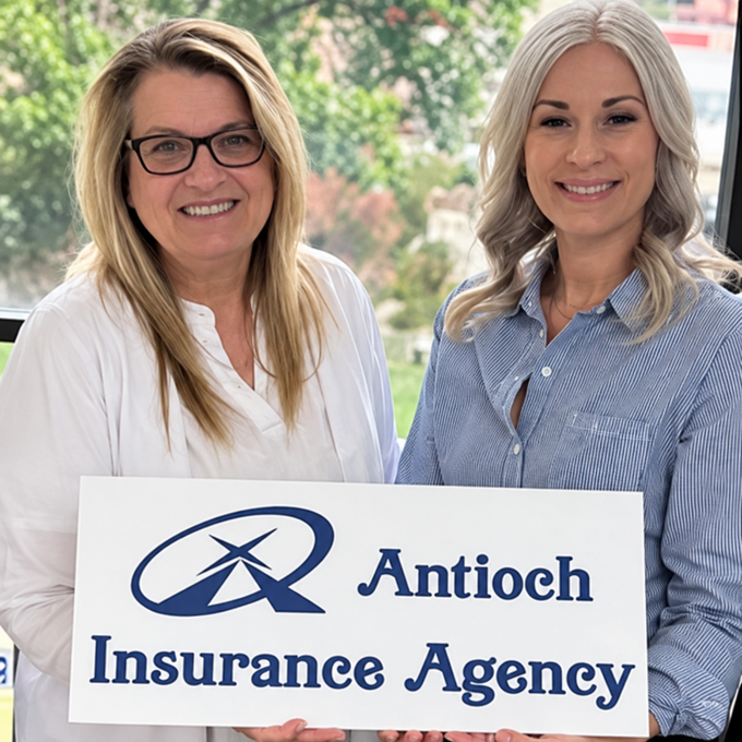 Three women hold an Antioch Insurance Agency sign, smiling inside by a window.