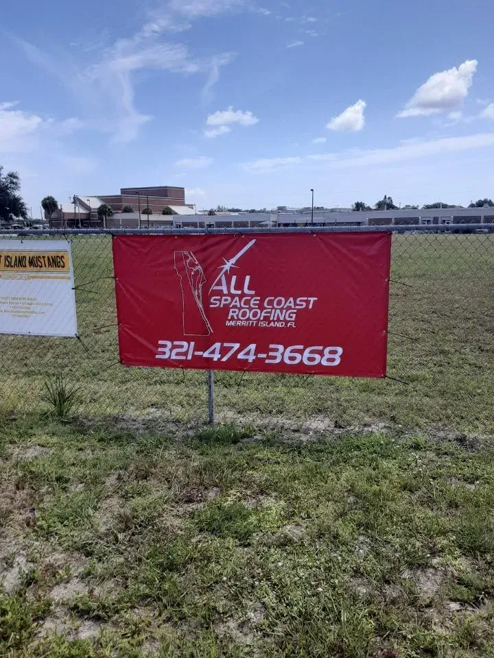 Red All Space Coast banner with phone number 321-474-3668 in a grassy field under a blue sky