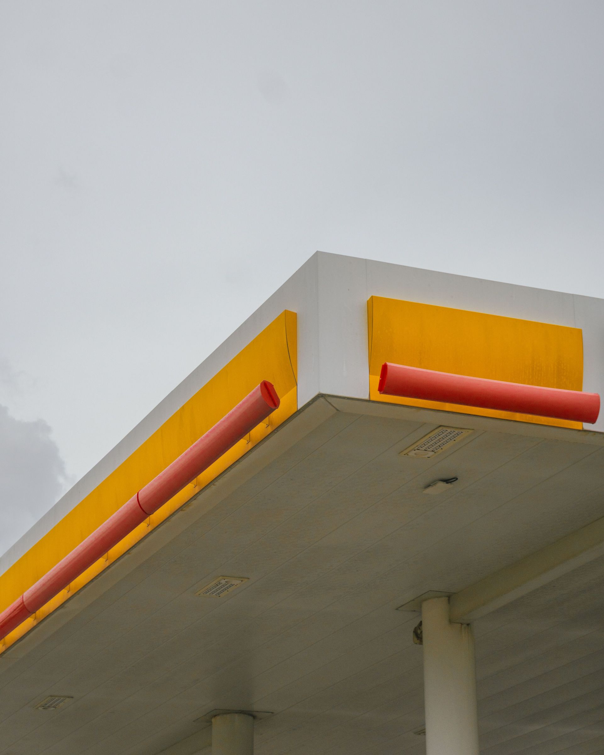 Yellow and white building corner with red trim against a gray sky